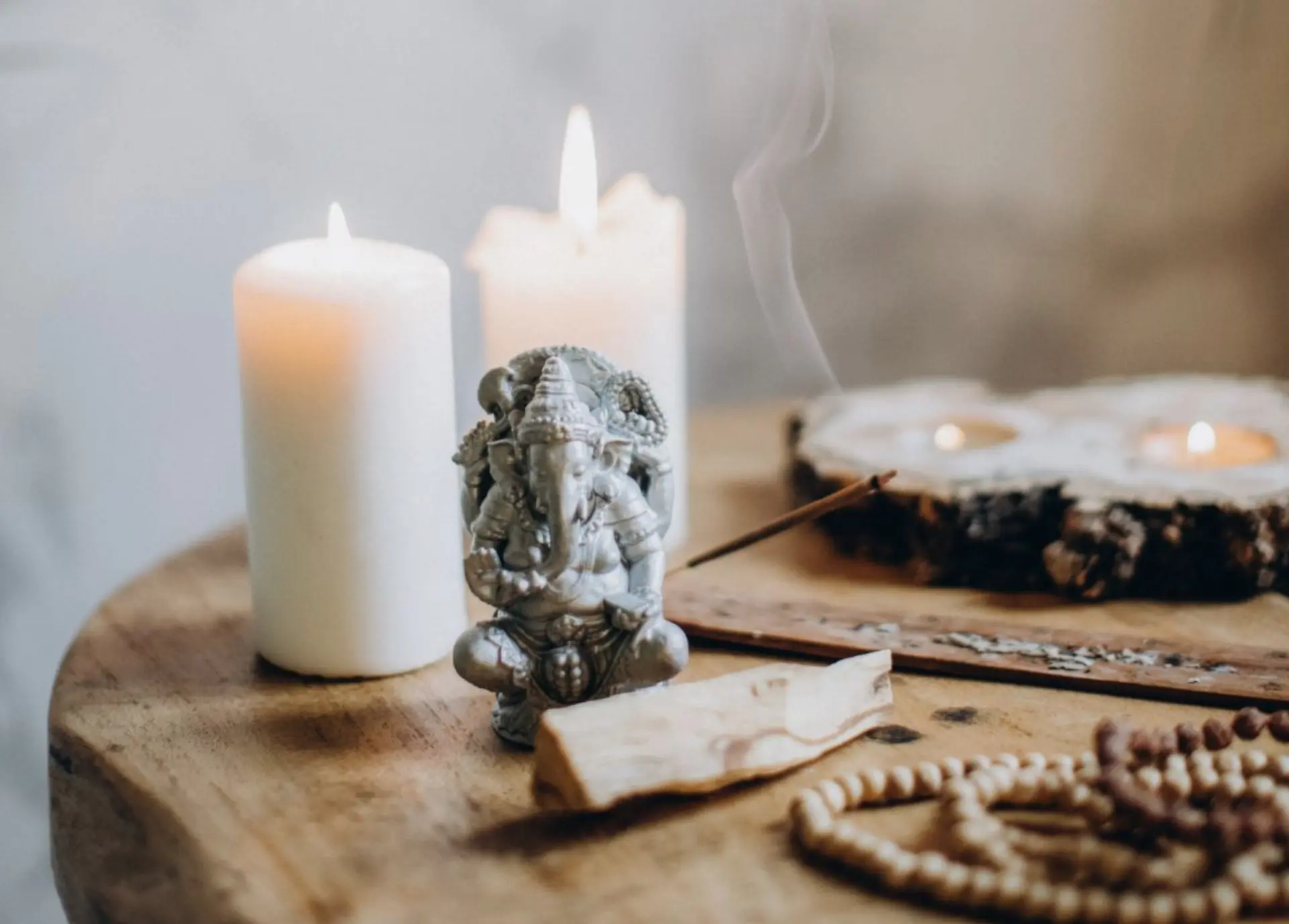 Ljus, rökelse och en liten Ganesha-figur på ett träbord